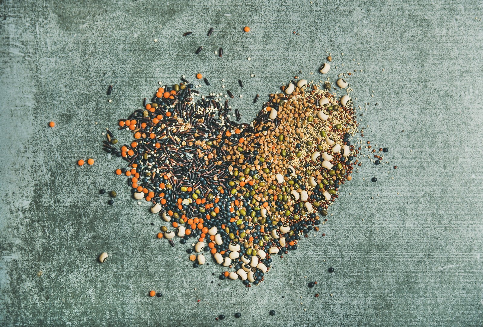 Various raw grains, beans and cereals in shape of heart